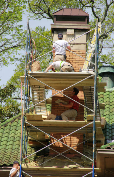 Coopertown technicians on scaffolding performing work on a masnory chimney